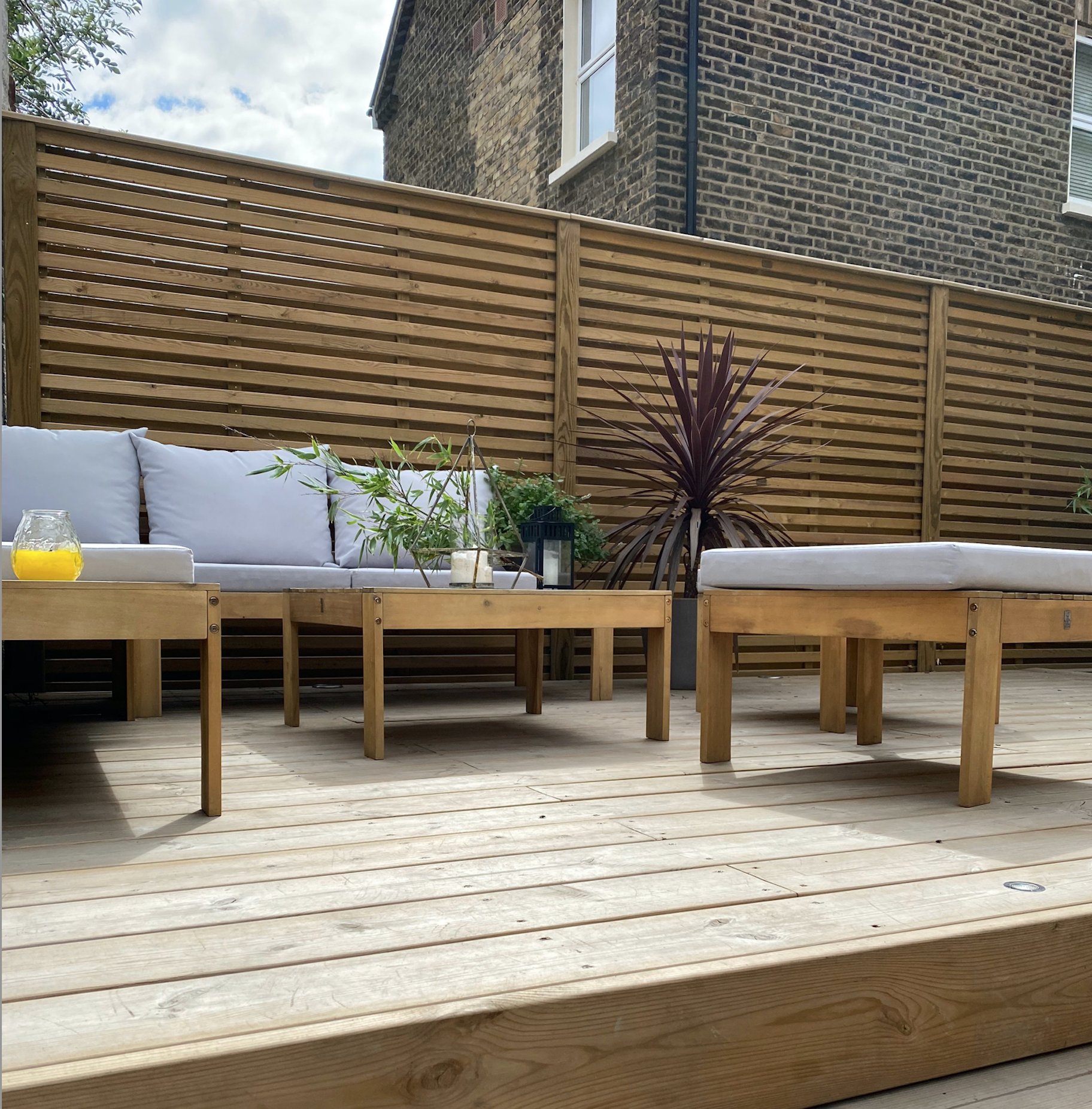 Venetian slatted fence installed by Tatton Fencing behind a decked garden seating area