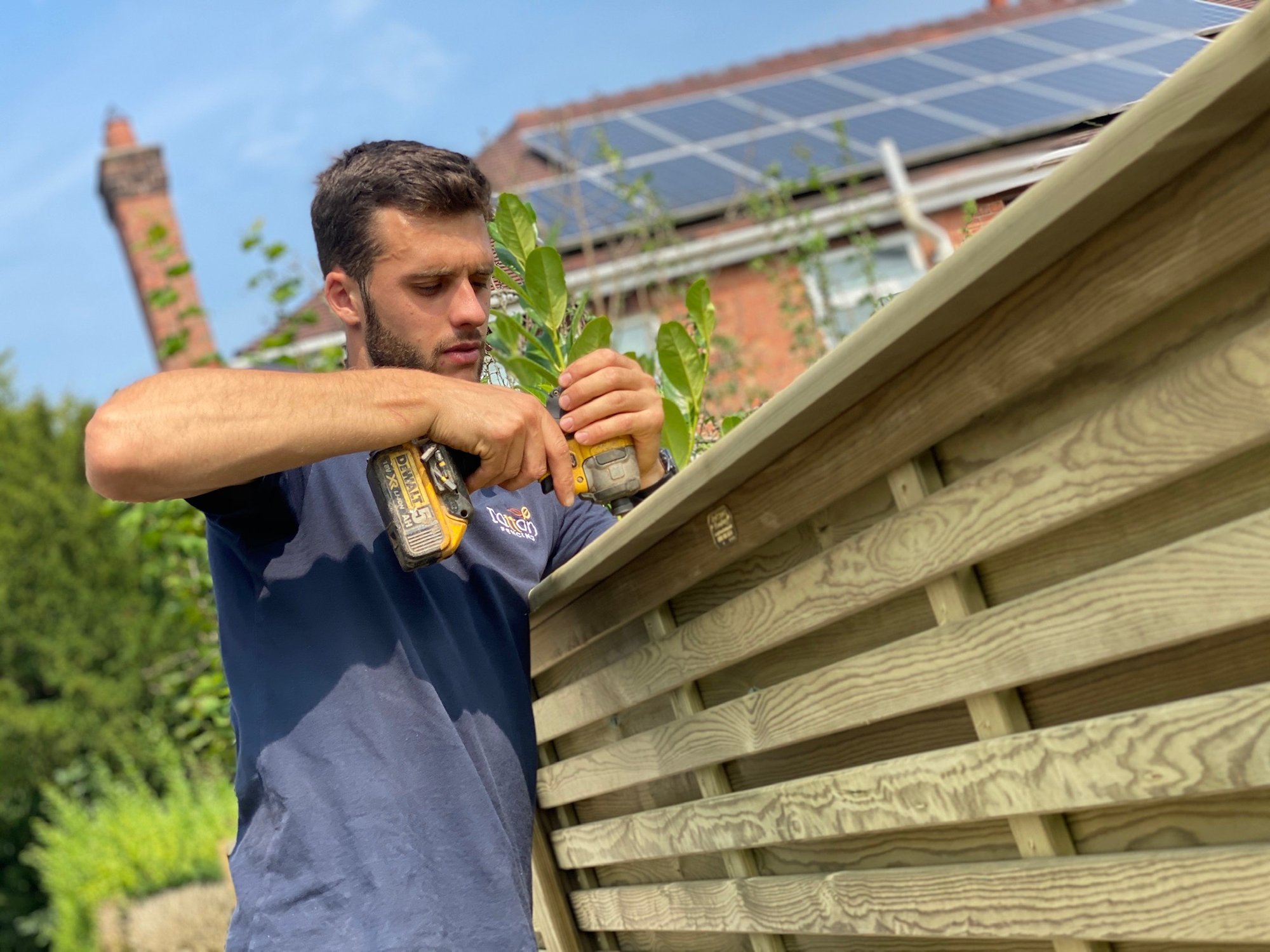 Tatton Fencing installer fixing the capping rail on a slatted fence panel